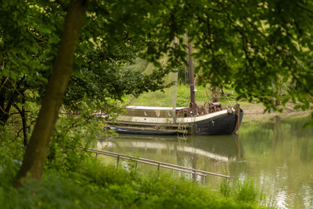 Calm river scene with a moored boat surrounded by lush greeneryの写真素材