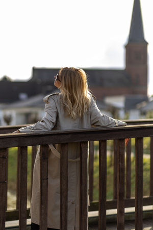 Woman enjoying a serene moment at a scenic viewpoint overlooking a historic church in the evening lightの写真素材
