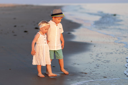 Children play at sunset on the beach, enjoying the waves and sand with joyful expressionsの写真素材