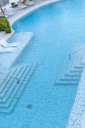 The serene pool features inviting crystal clear water and elegant steps leading down. A fun slide...