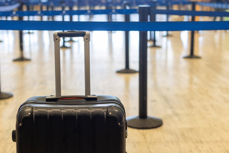 Black suitcase waiting in line at Punta Cana airport during busy travel seasonの写真素材