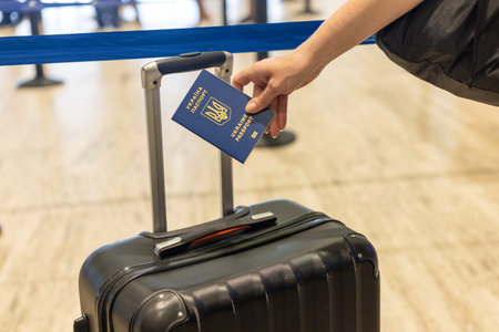 Traveler checks passport before boarding flight at airport during busy afternoon hoursの写真素材