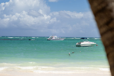 Calm day at the beach with boats floating in turquoise waters under a bright blue skyの写真素材