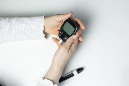 Monitoring blood glucose levels with a glucose meter at home in daylight hoursの写真素材