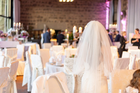 Elegant wedding celebration with the bride standing gracefully in a beautifully decorated venue during a festive eveningの写真素材