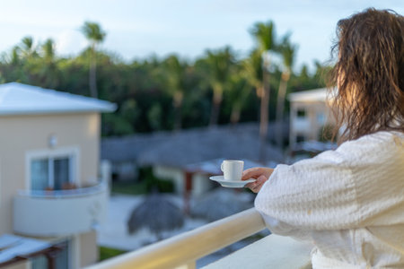 Relaxing morning with coffee on a balcony overlooking tropical resort, surrounded by palm trees and cloudless skiesの写真素材