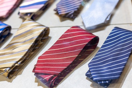 Display of assorted neckties showcasing modern styles and colors in a retail store during daylightの写真素材
