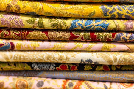Colorful embroidered fabrics stacked neatly in a textile shop showcasing intricate designsの写真素材