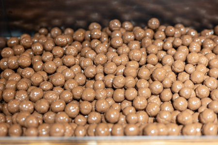 Production of shiny chocolate candies in a modern factory during daytime hours with a focus on...