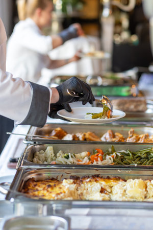 Catering staff serve delicious food at an upscale event buffet during a sunny afternoonの写真素材