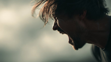 Intense man expressing emotions during a dramatic moment outdoors under cloudy skiesの素材