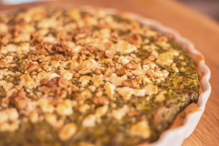 Delicious green herb tart topped with nuts in a cozy kitchen during a sunny afternoon cooking...