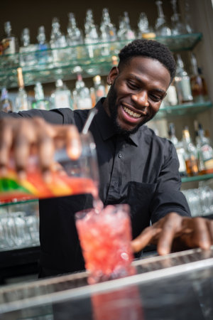 Bartender pouring a colorful drink at a busy bar during a lively eveningの素材