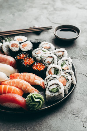 Delicious sushi platter featuring various rolls and sashimi served with soy sauce and wasabiの素材