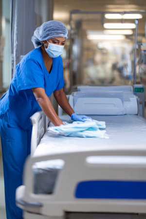 Nurse prepares a hospital bed in a busy medical facility during evening shift hoursの素材