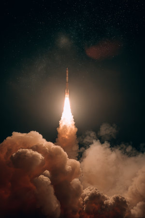 Rocket launches into night sky, illuminating clouds with bright flames and showcasing human engineering and explorationの素材