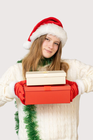 Festive girl in Santa hat holding Christmas gifts with joy during holiday seasonの写真素材