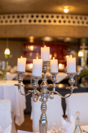 Elegant candelabra with lit candles at a beautifully set dining table in a warm restaurant during an evening eventの写真素材
