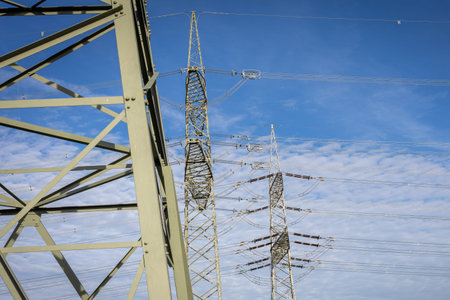 Electric transmission towers against a blue sky with wispy clouds in a clear daylight setting