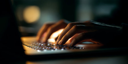 Hands closing a laptop at the end of a workday in ambient lighting creating a serene atmosphereの素材