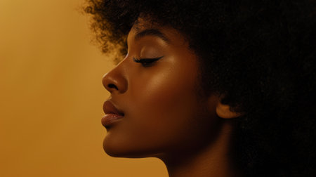 Beautiful profile of a woman with curly hair against a warm orange background capturing elegance and gracefulnessの素材