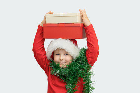 Child wearing a Santa hat holds gift boxes with excitement during a festive holiday celebrationの写真素材