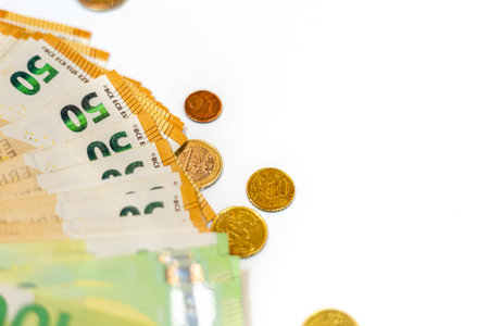 Collection of colorful banknotes and coins laid out on a white surface in a neat arrangement