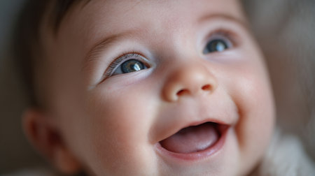 Joyful baby smiles brightly while lying on soft blanket indoors in warm light during early afternoonの素材