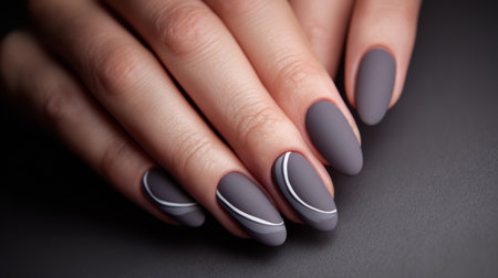Elegant matte gray manicure with artistic white line design on well-groomed handsの素材
