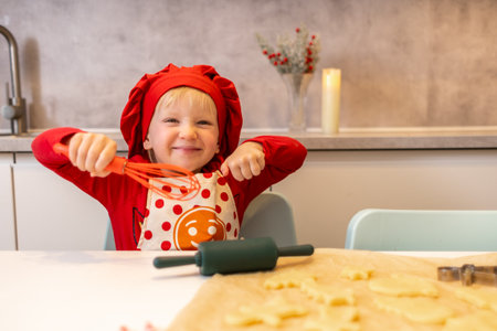 Young chef enjoying baking cookies in a bright kitchen during a fun family activityの写真素材