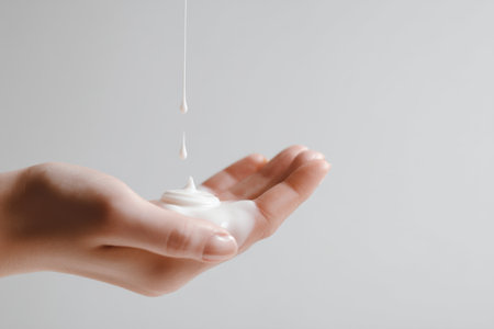 Creamy lotion being dispensed from a bottle into a hand for skincare at homeの素材