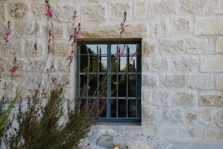 Window in a ancient stone wall with flower bushの写真素材