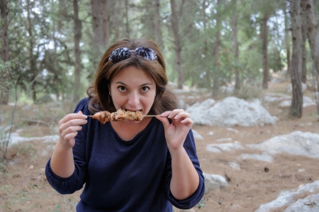 woman bites a grilled kebab outsideの写真素材