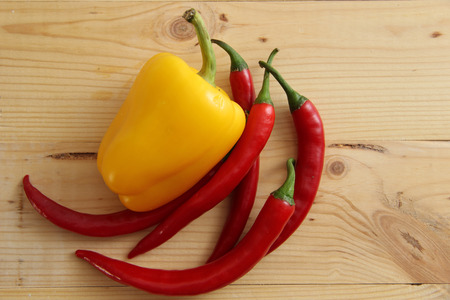 red hot burning, and yellow sweet peppers on a wooden boardの写真素材