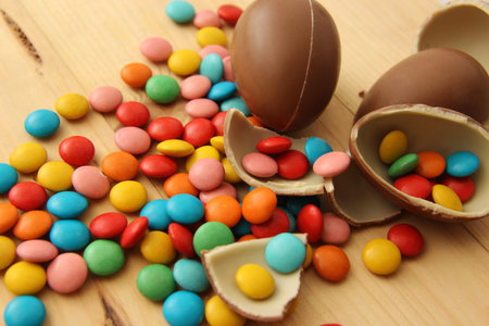 bright colorful round candy M & M's and chocolate eggs on wooden boards