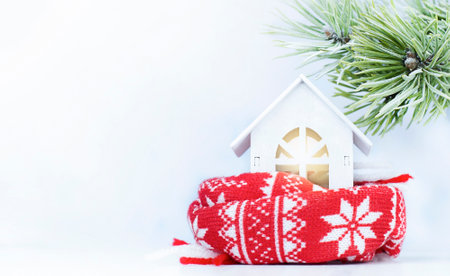 a small house in a scarf under a pine branch. heating conceptの写真素材