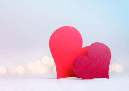 two red valentines in the form of hearts on a light defocus backgroundの写真素材
