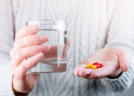 girl holding pills and a glass of water in her handsの写真素材