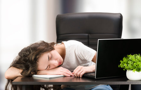 the woman is tired and lies on the desktop at home