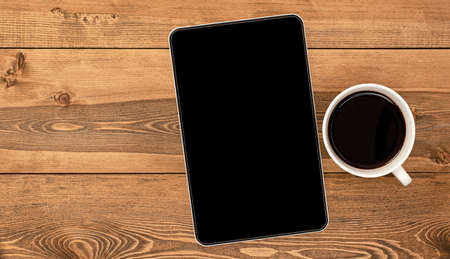 tablet computer and coffee cup on wooden tableの写真素材