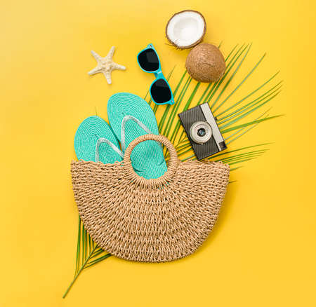 composition of a beach bag, flip-flop, camera, palm leaf, sunglasses, coconut and starfish on a yellow background. summer conceptの写真素材