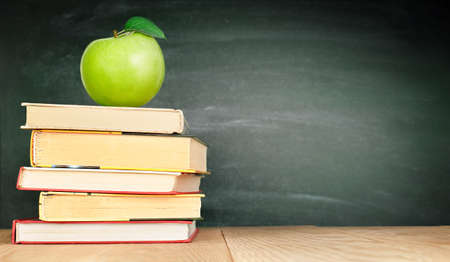 one apple on the books on the background of the school boardの写真素材