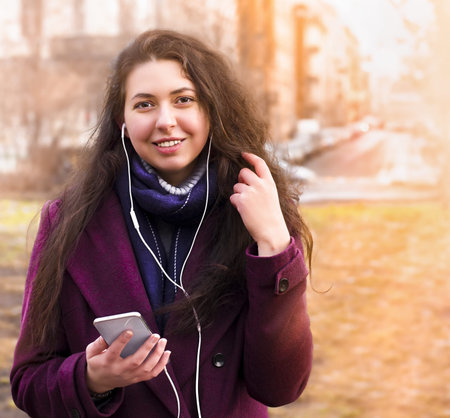 portrait of happy young woman in headphones on city street