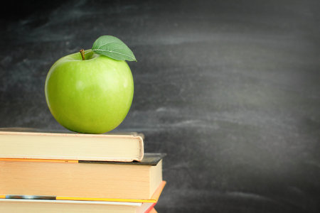 one green apple on books in the classroom