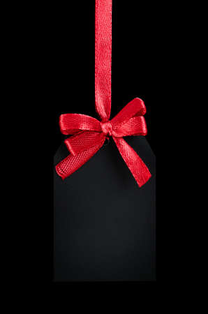 black tag with red bow on black isolated backgroundの写真素材