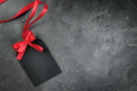 one black label with red bow on gray concrete backgroundの写真素材