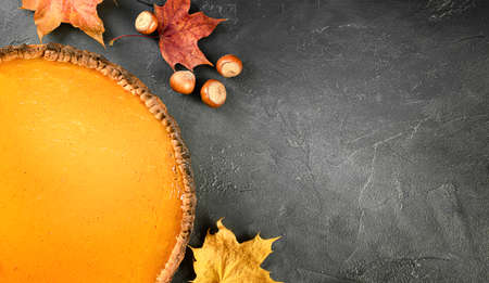 pumpkin pie, hazelnuts and autumn leaves on a dark backgroundの写真素材