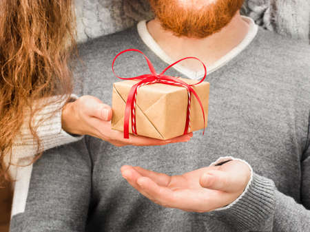 woman's hand gives a gift box to a man close-upの写真素材