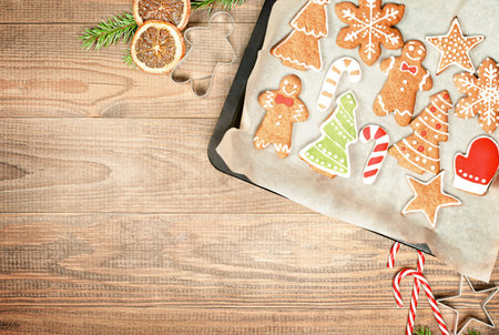 christmas gingerbread on a baking sheet and christmas decorations on a wooden table