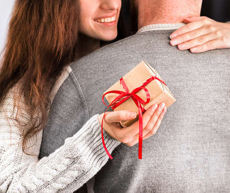 woman with a gift in her hand hugs a man, close-upの写真素材